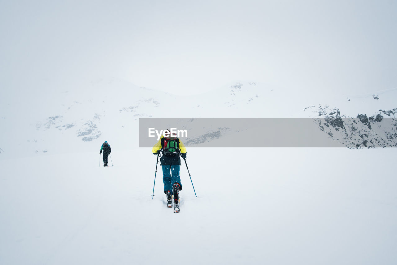 Rear view of man skiing on snow covered land