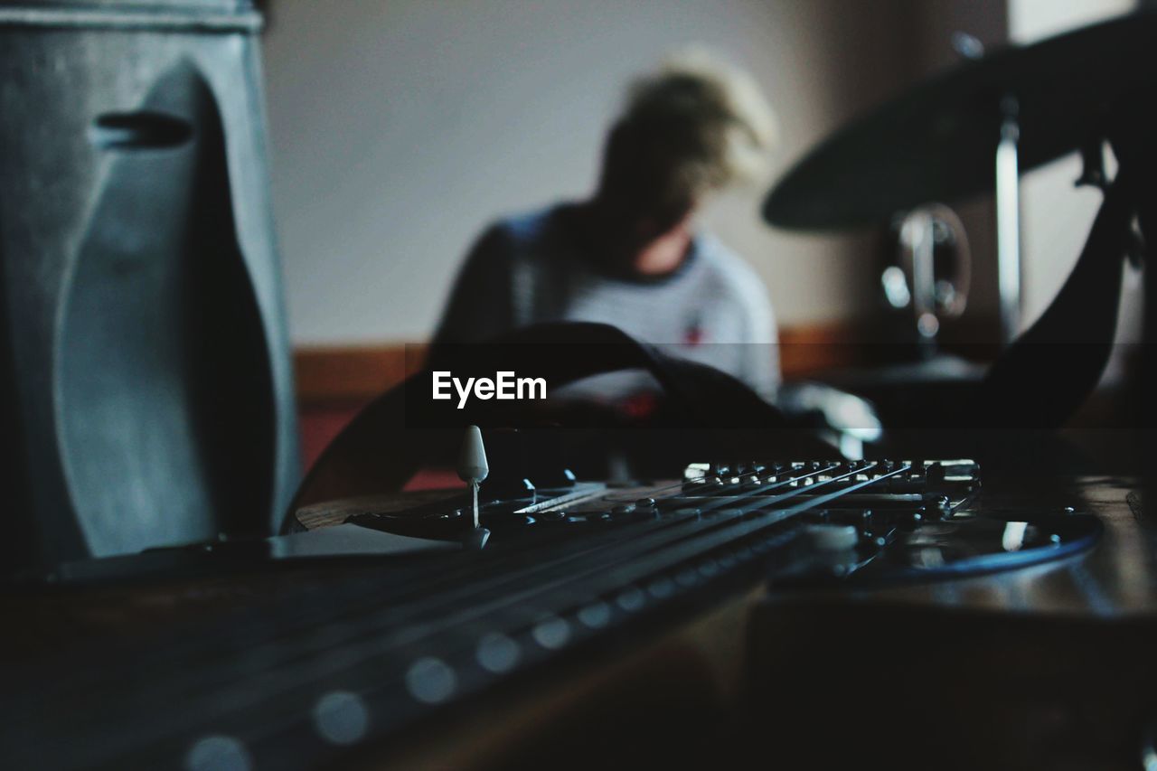 Close-up of musical equipment with woman sitting in background