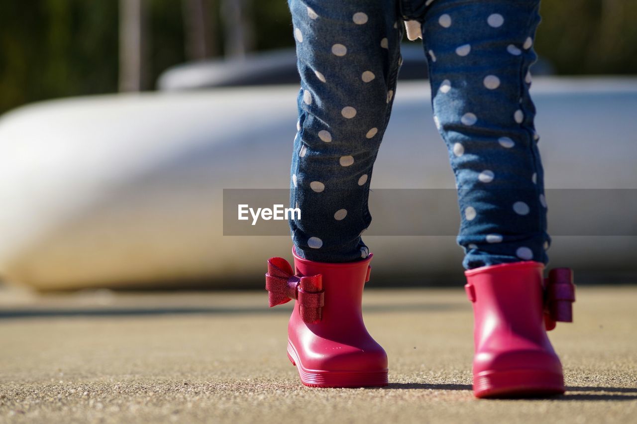 Low section of child with pink shoes walking on road