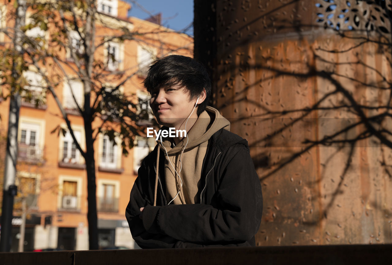 Asian teenage boy with earphones on street. madrid. spain