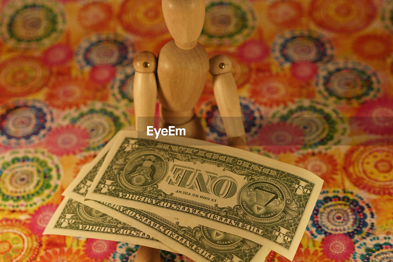 Wooden figurine with currencies on designed paper