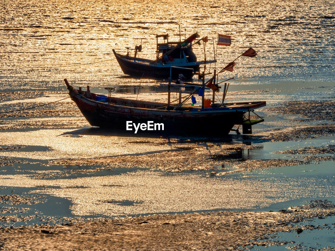 The old wooden fishing boat on a pebble beach on beautiful sunrise.