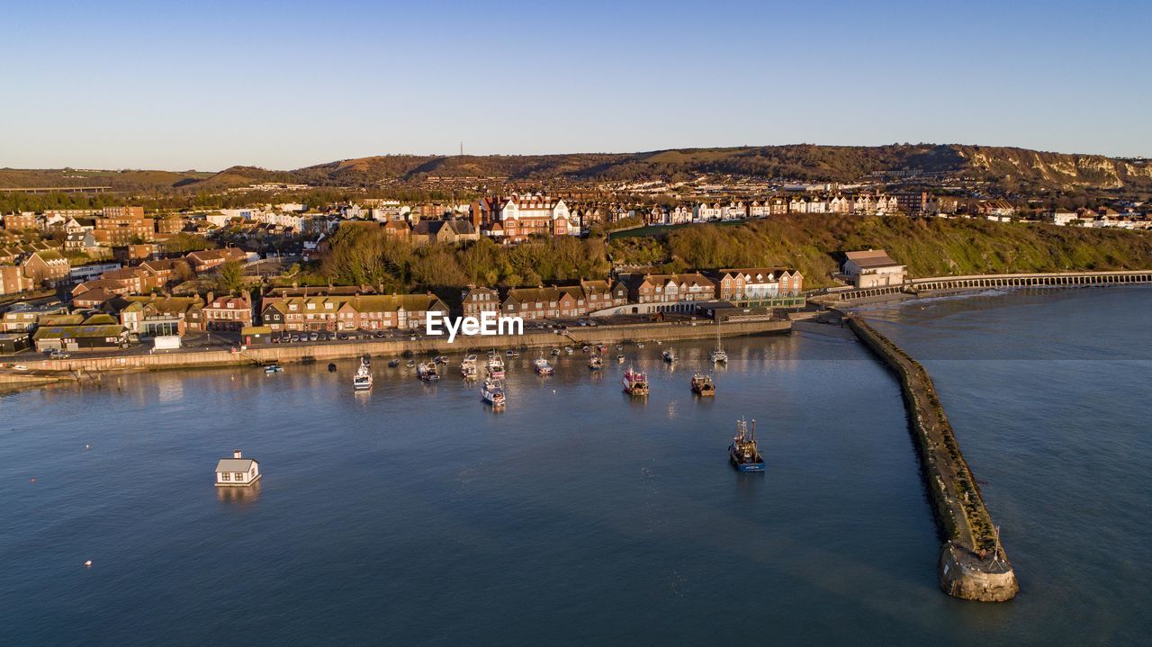 Aerial view of townscape by lake against clear blue sky