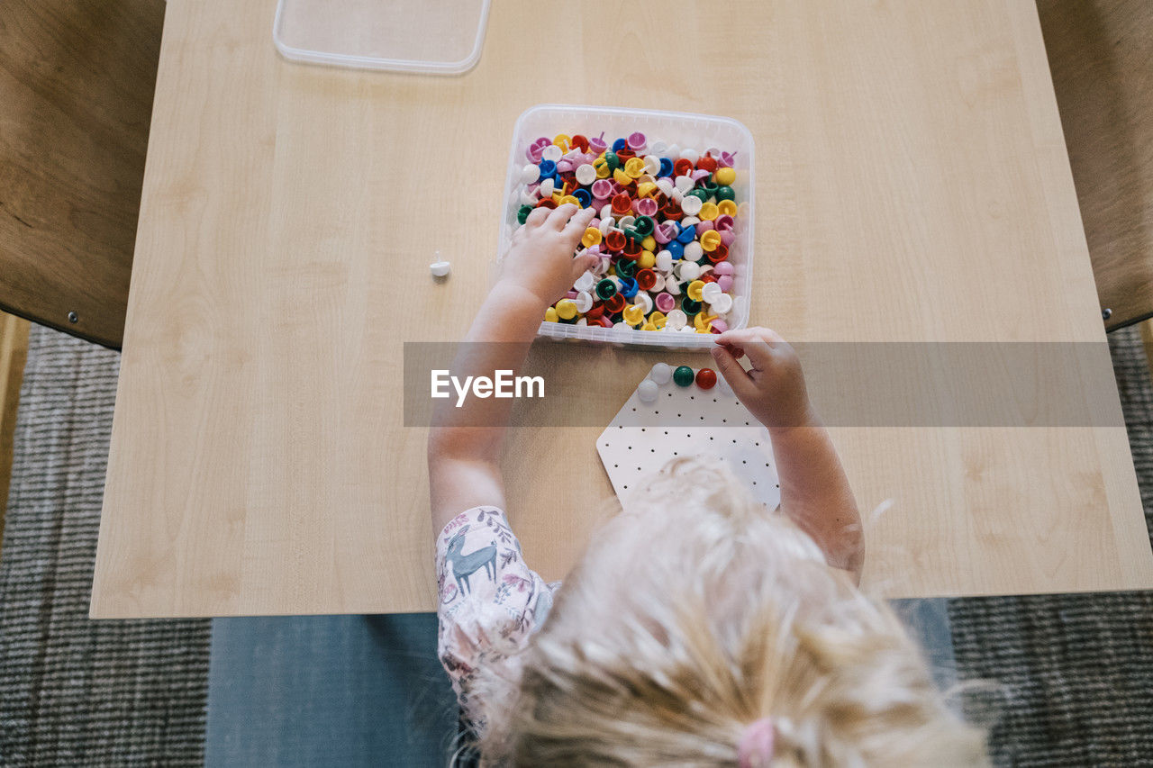 Directly above shot of girl playing pegboard game on table