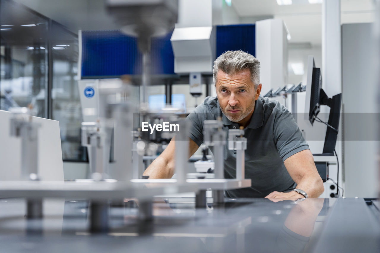 Engineer with gray hair examining machinery in factory