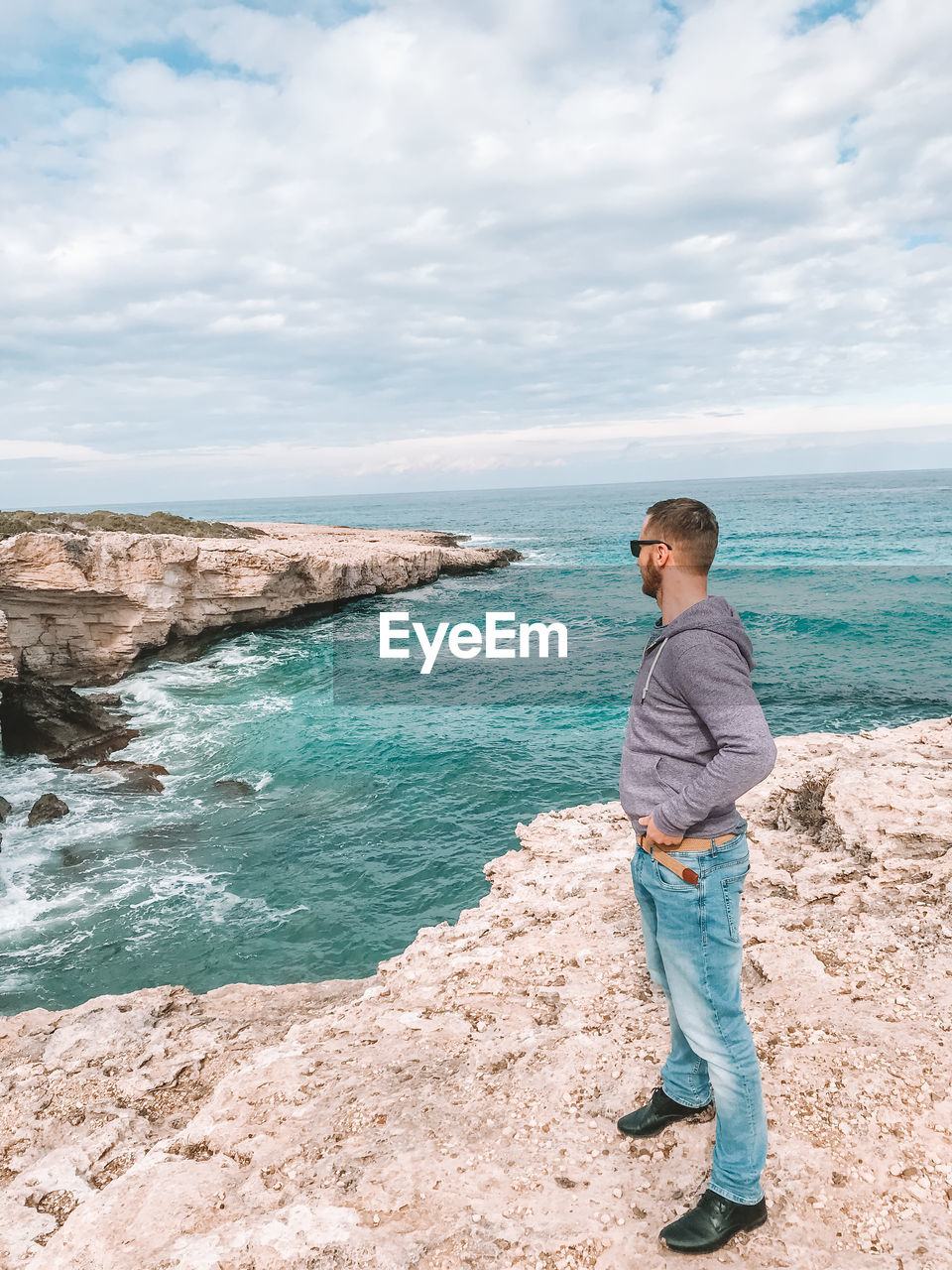 FULL LENGTH OF MAN STANDING ON ROCK IN SEA