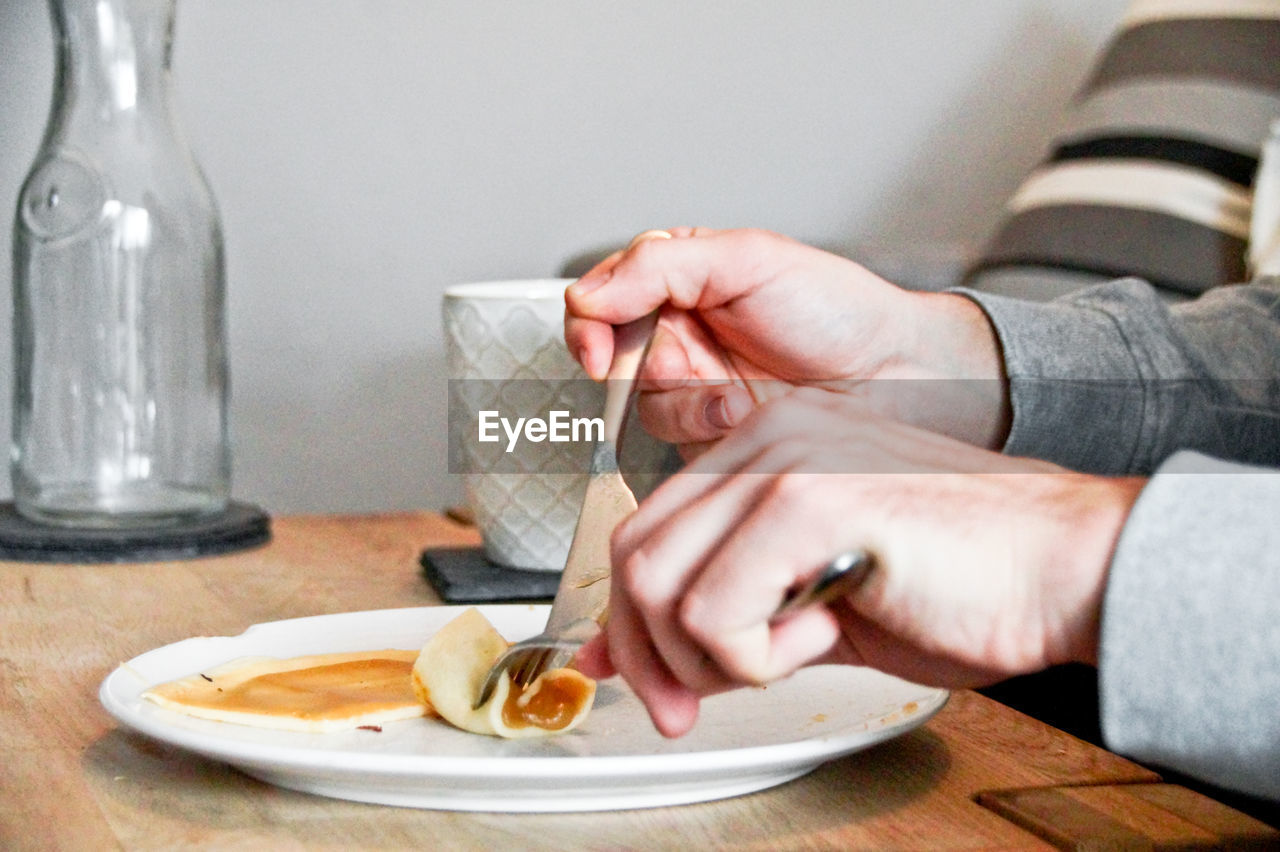 Cropped hand eating food on table
