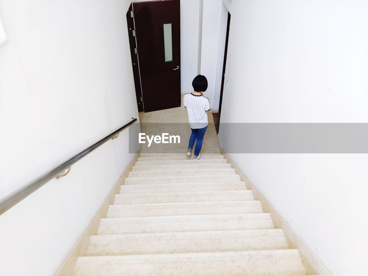 REAR VIEW OF MAN STANDING ON STAIRCASE