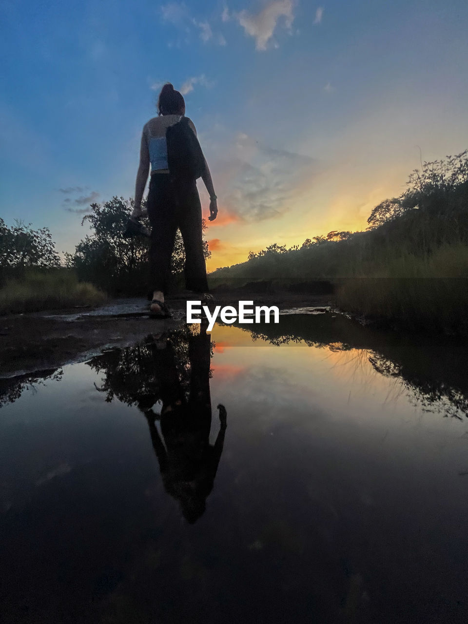 reflection, water, sky, one person, lake, nature, adult, morning, beauty in nature, men, tranquility, full length, silhouette, activity, leisure activity, scenics - nature, dusk, cloud, lifestyles, landscape, tranquil scene, sunlight, tree, mountain, standing, sunrise, plant, outdoors, environment, twilight, sun, rear view, rural scene, person, adventure, land, vacation, holiday, occupation, trip