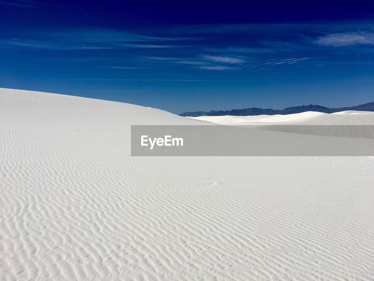 Scenic view of sand dunes at beach against sky