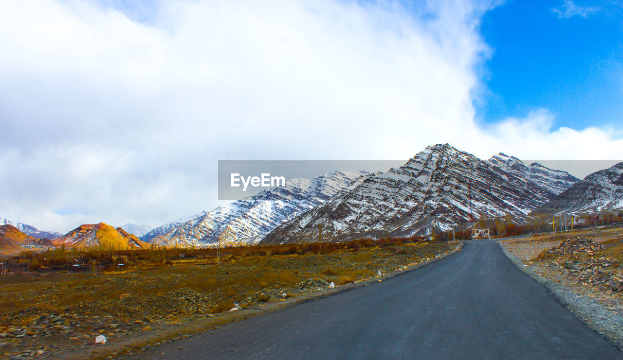 Road amidst snowcapped mountains against sky