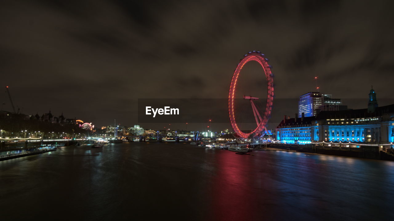 Illuminated ferris wheel in city at night - london eye