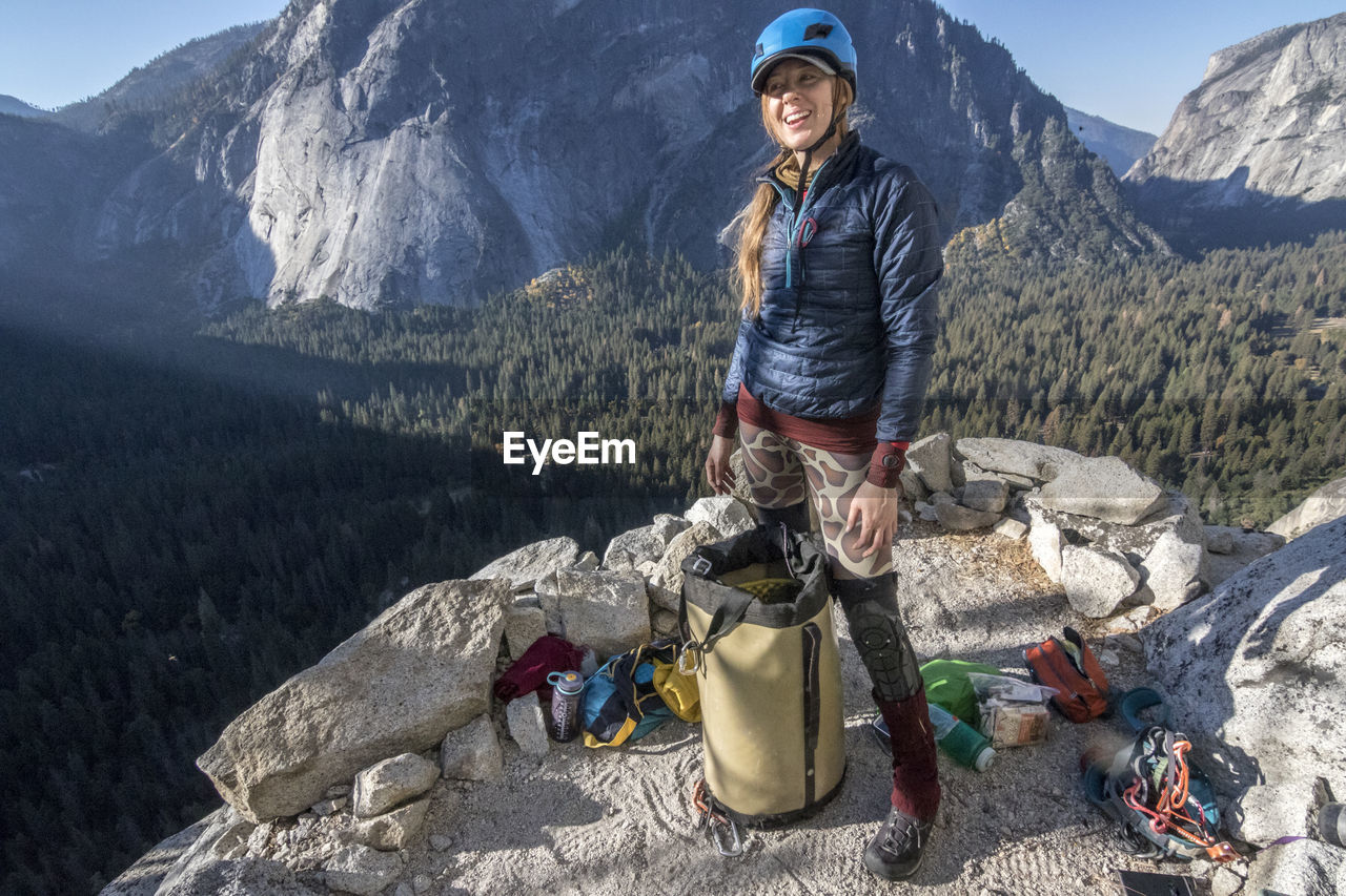 A young woman climber smiles as she stands on last night's bivy ledge