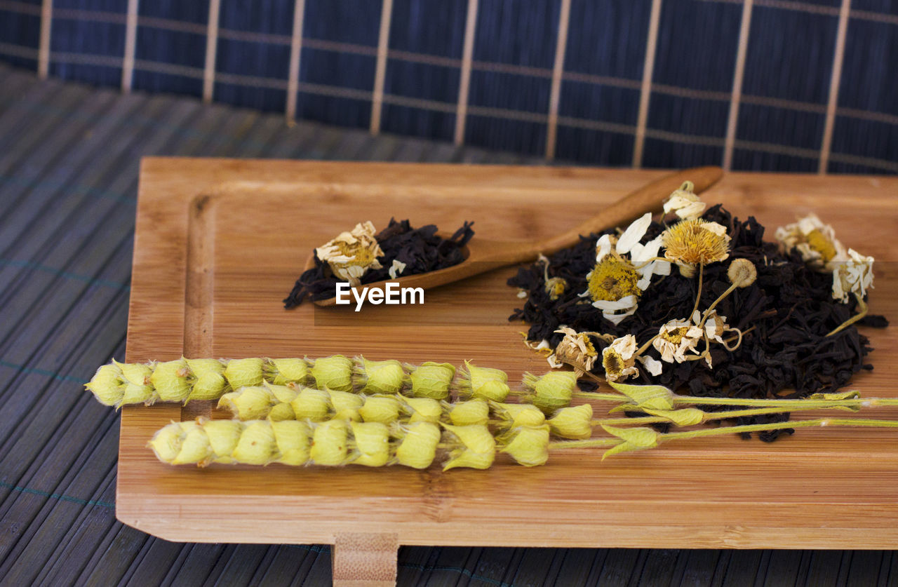 Black friable tea with the sage salvia and chamomile. on wooden spoon on tray