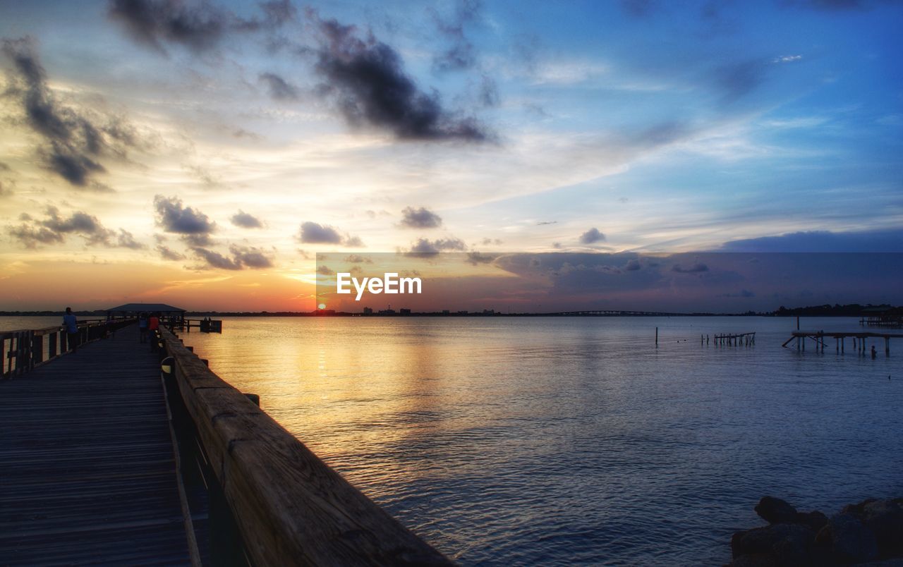 Pier over sea against sky during sunset