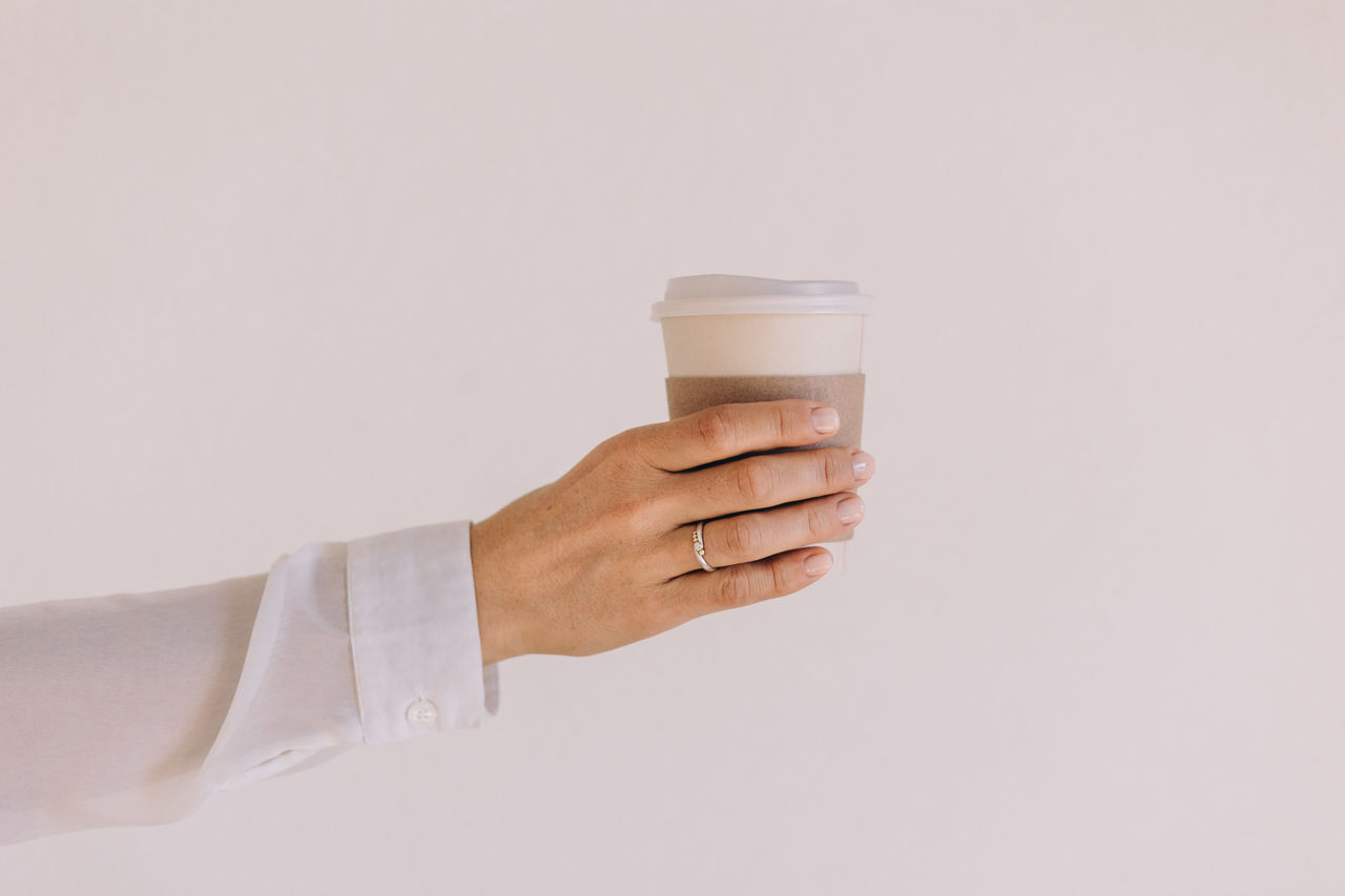 Female hand holding a to go cup in front of a white background