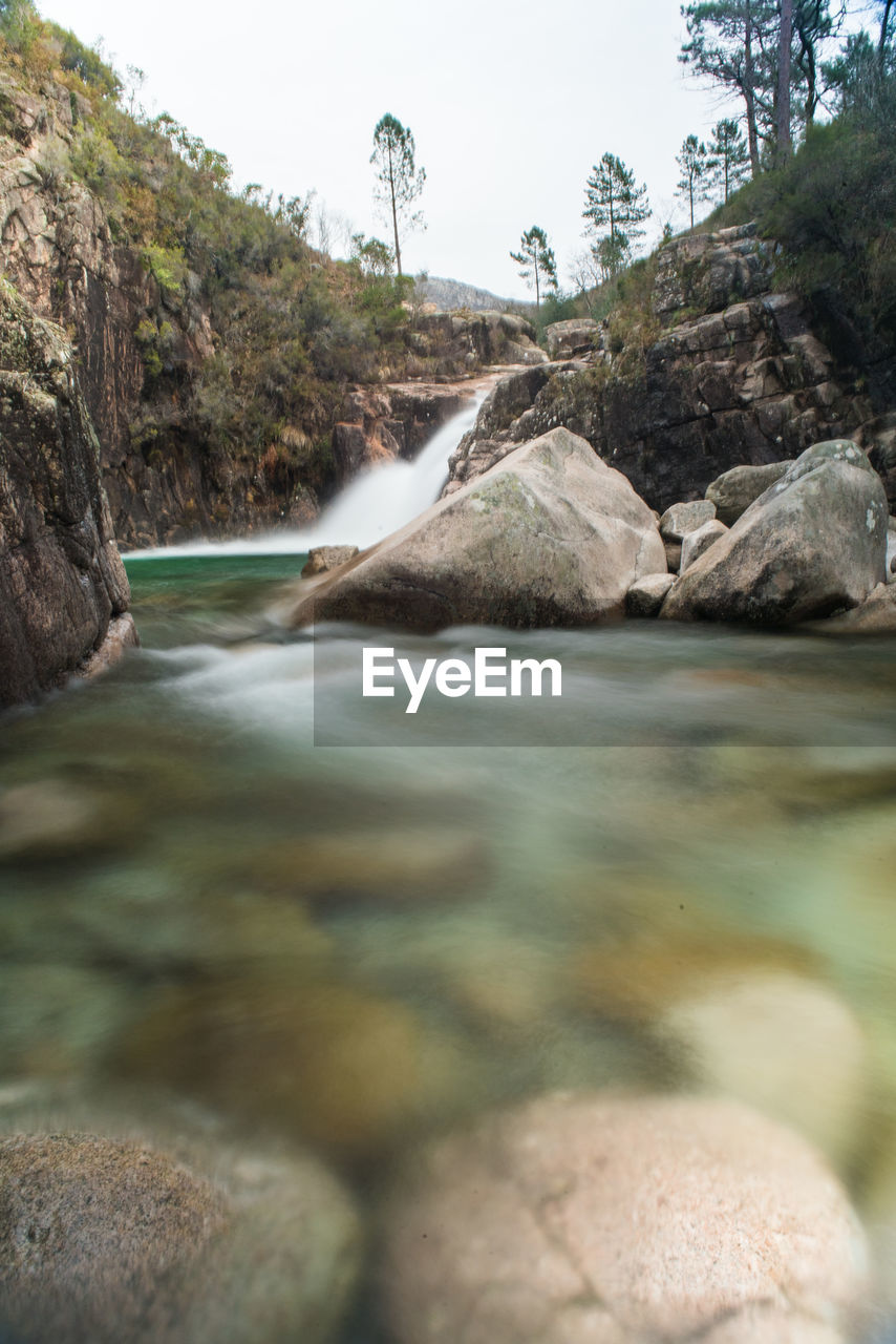 Scenic view of river stream through rocks in forest