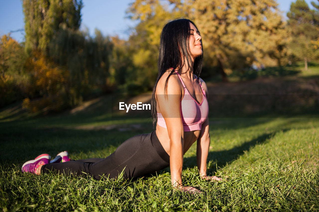 Young girl practices yoga in the park on the grass.