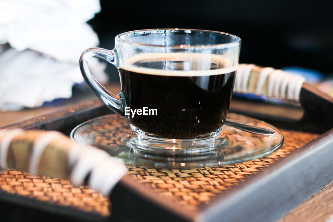 Close-up of cup of black coffee served in glass cup on tray