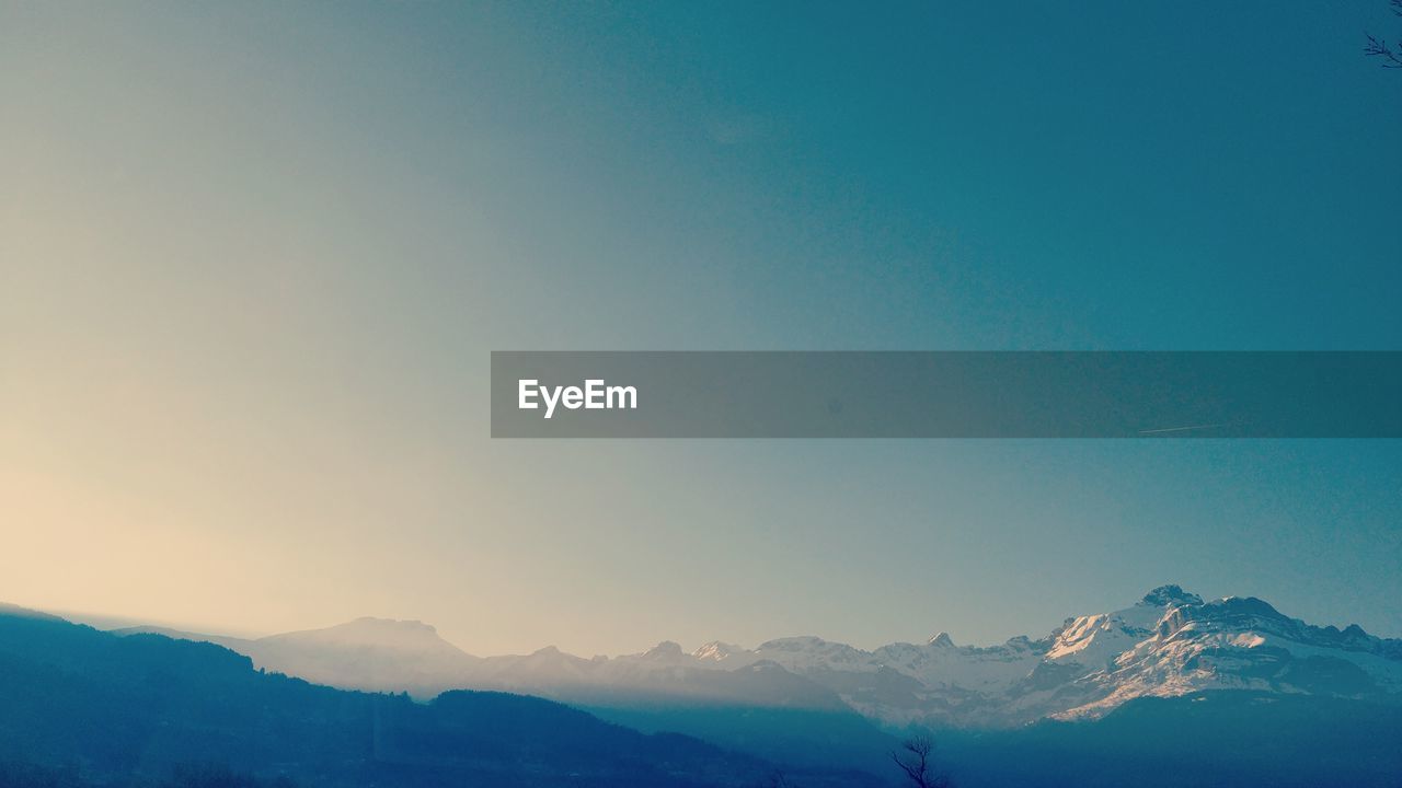 Scenic view of snowcapped mountains against clear blue sky