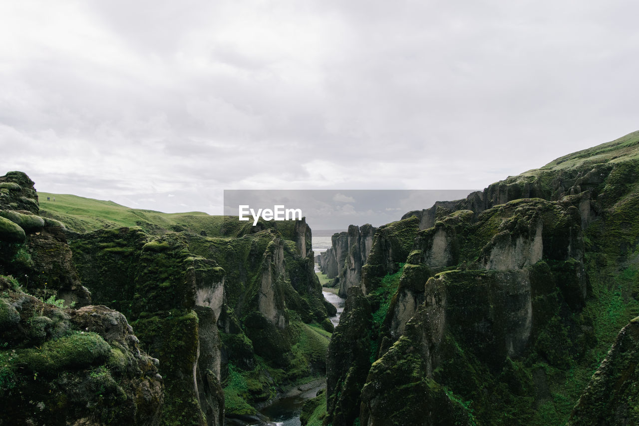 Scenic view of cliff against cloudy sky