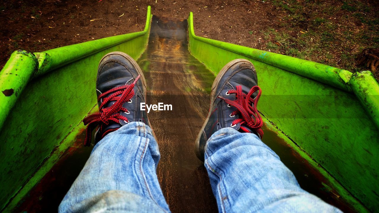 Low section of man sliding on slide at playground