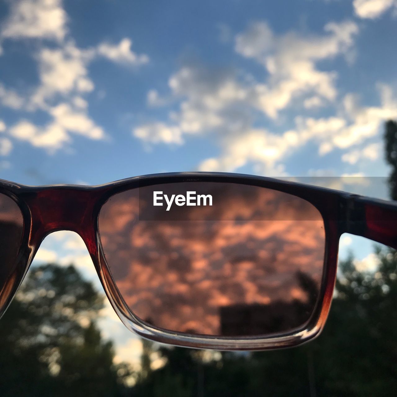 CLOSE-UP OF SUNGLASSES WITH REFLECTION ON MIRROR AGAINST SKY