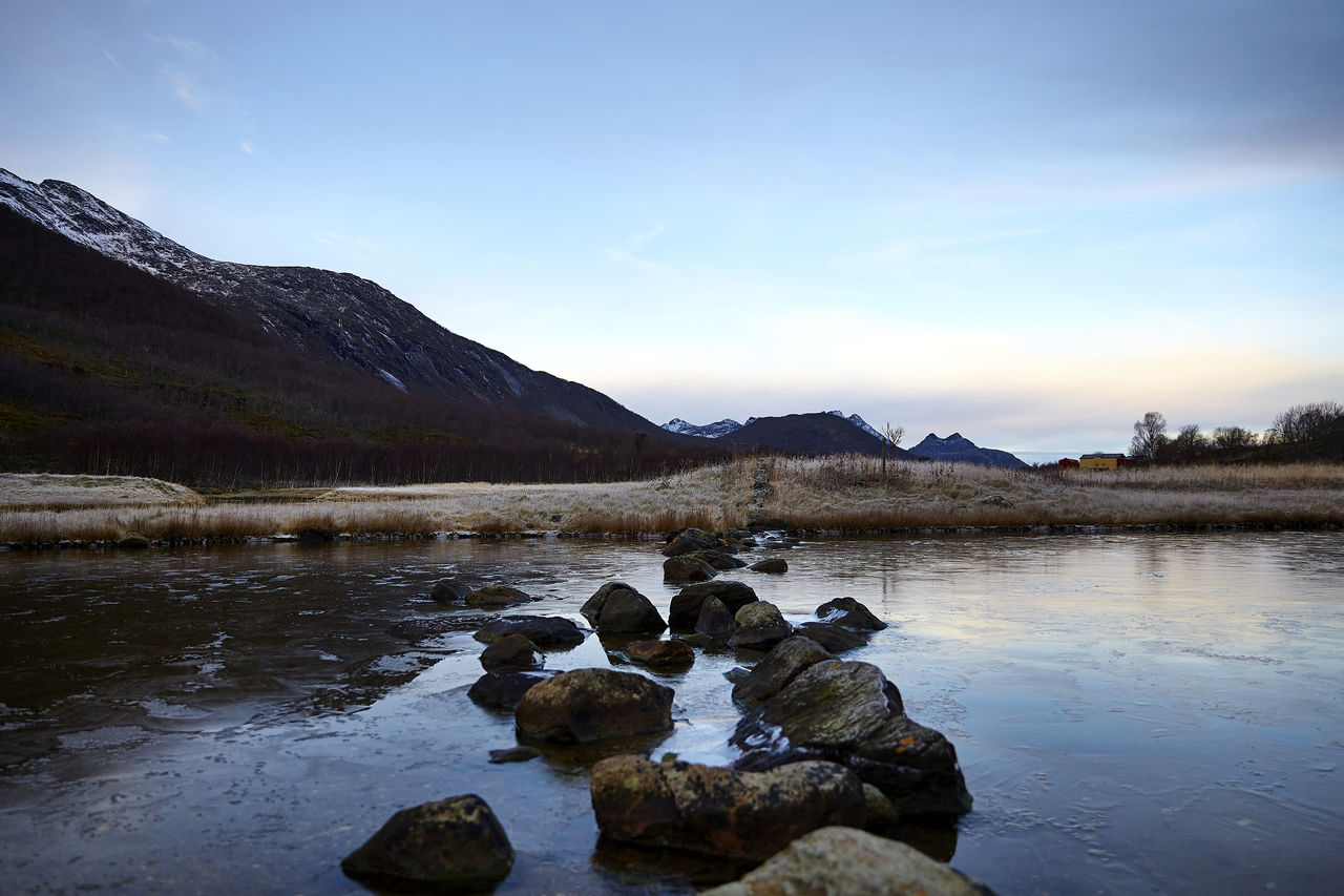 ROCKS BY LAKE AGAINST SKY