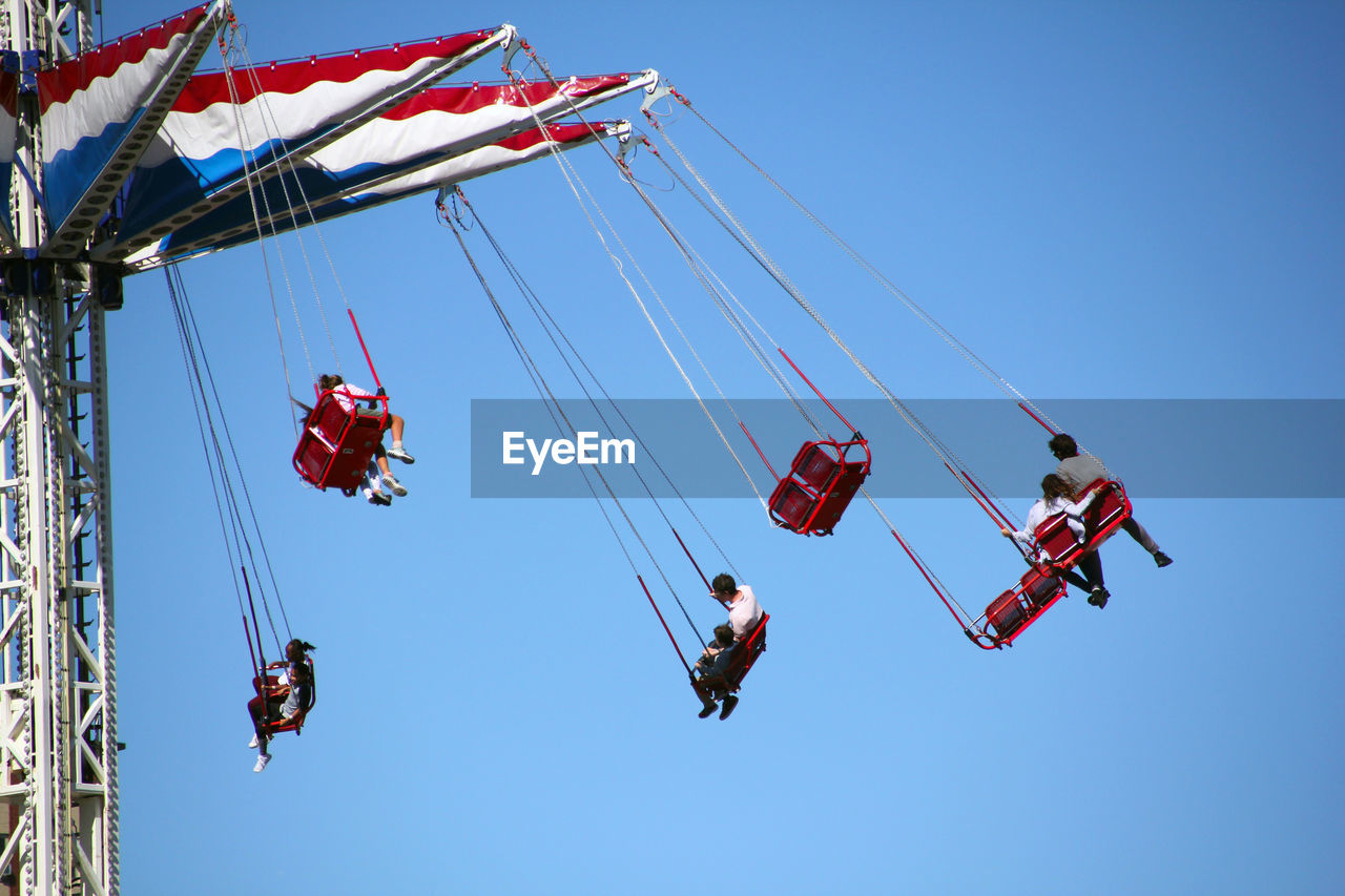 Low angle view of people on chain swing ride