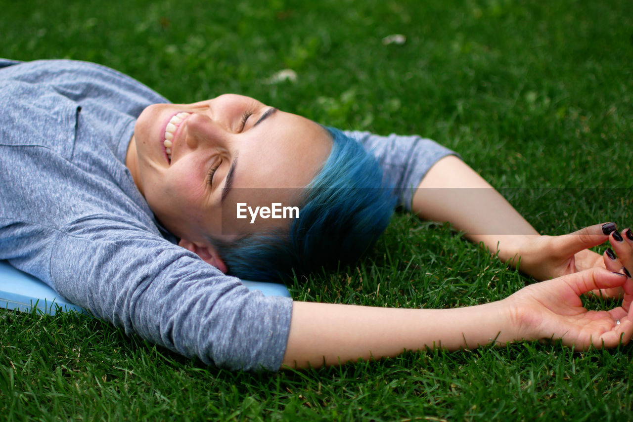 Happy young woman sleeping on grassy field