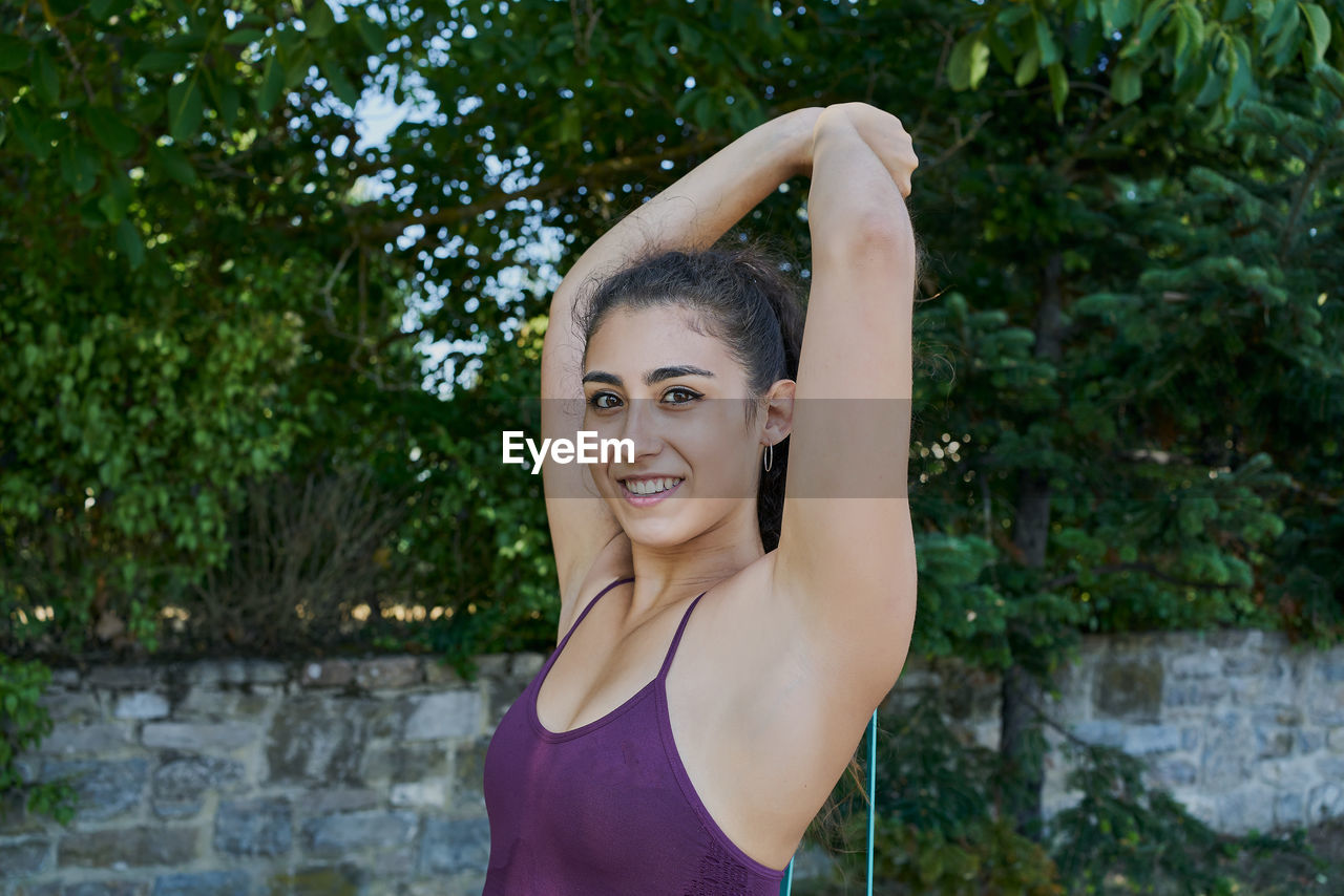 Young woman practicing calisthenic with an elastic band in a park