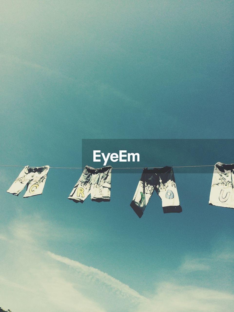 Low angle view of pants hanging on clothesline against sky