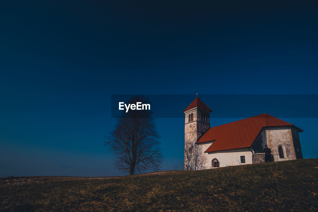 CHURCH BY BUILDING AGAINST BLUE SKY