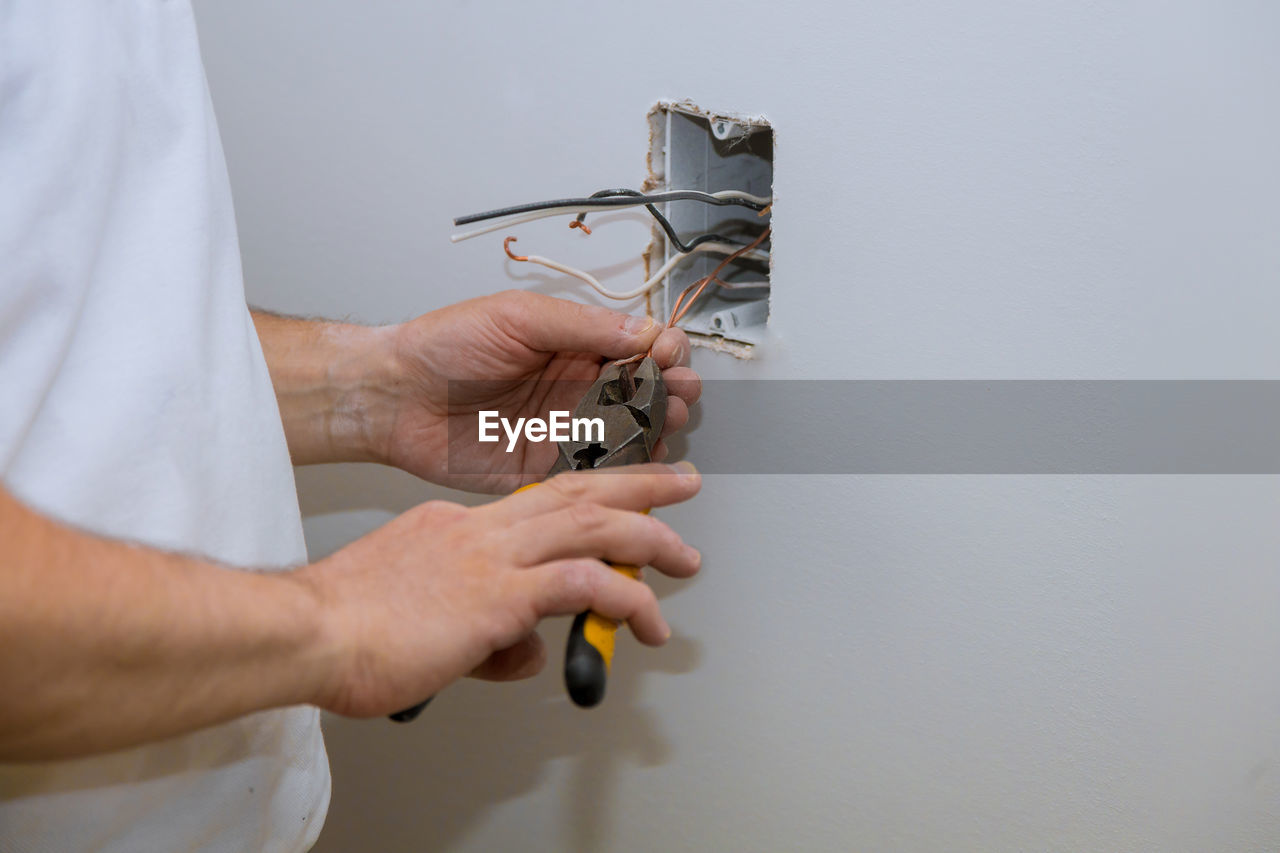 Midsection of man working while standing against wall