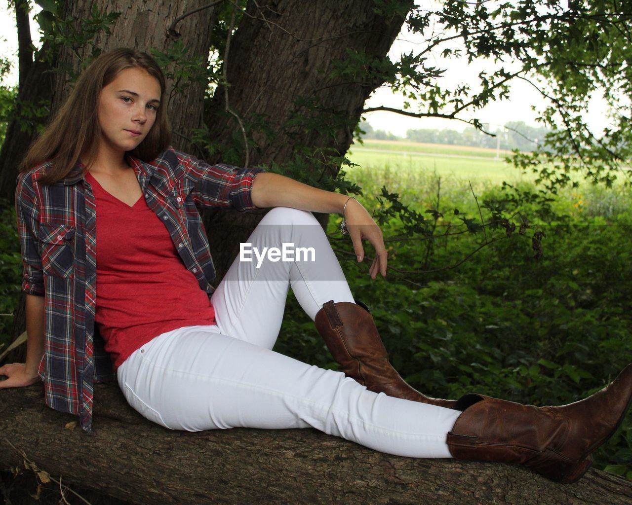 Portrait of young woman sitting on log in forest