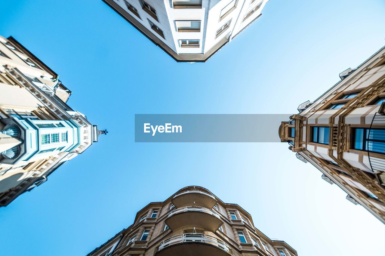 Directly below shot of buildings against blue sky