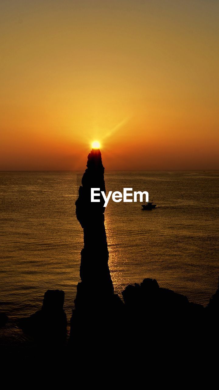 Silhouette of rocks on beach during sunset