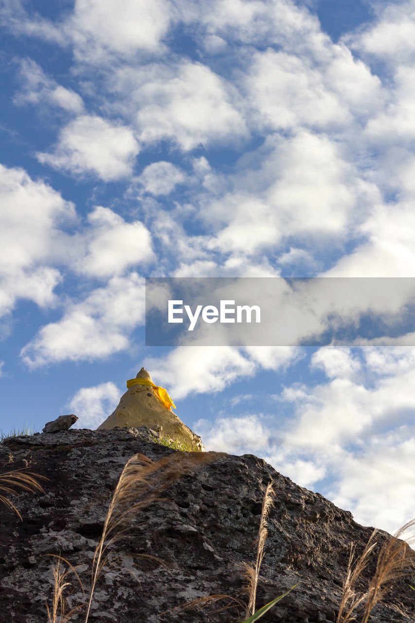 Low angle view of rocks against cloudy sky