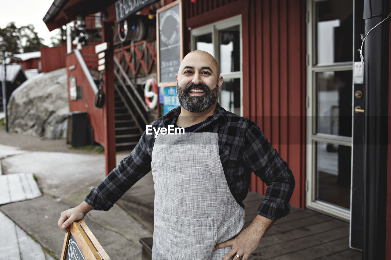 Portrait of smiling worker standing against factory