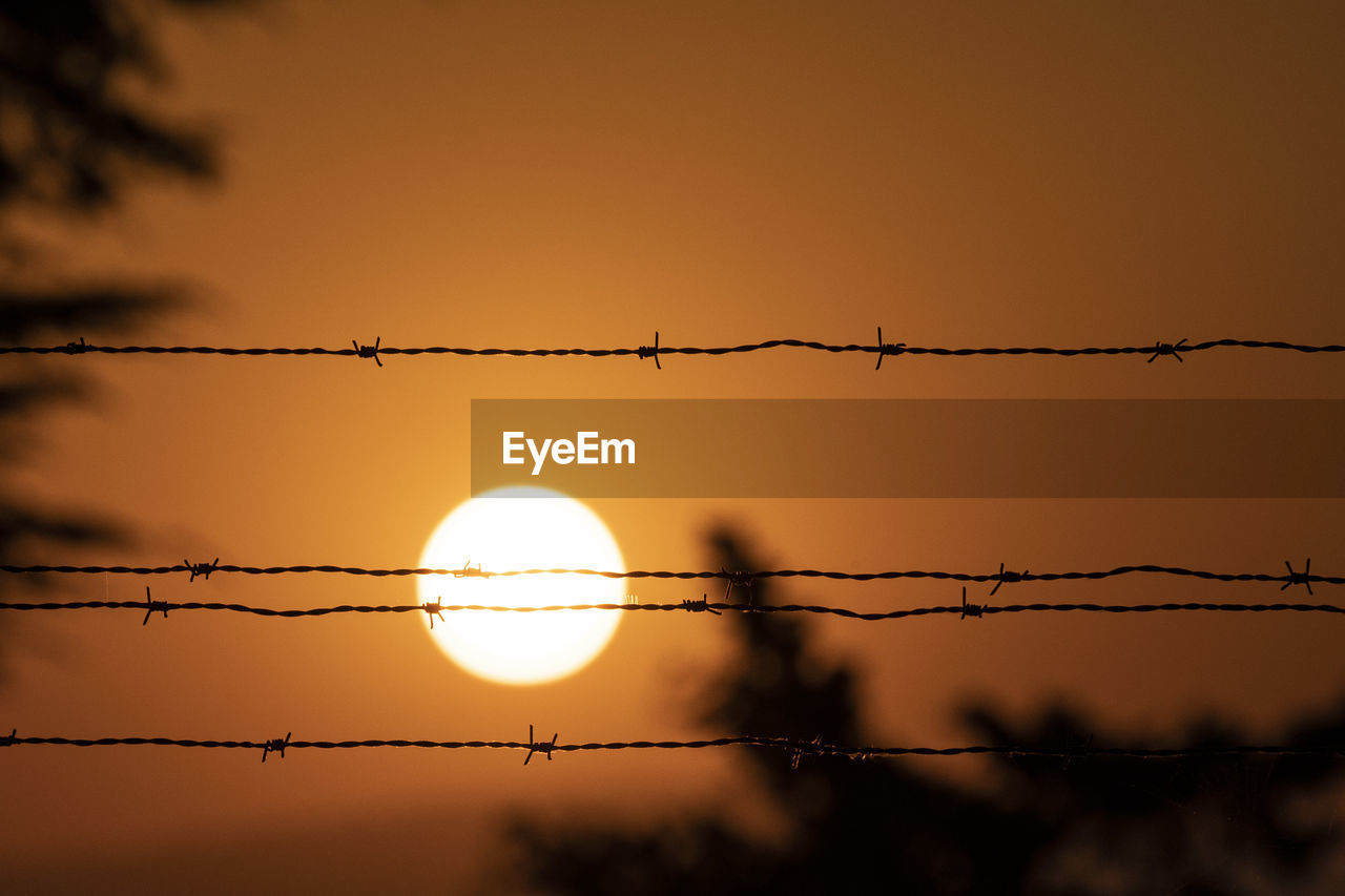 Low angle view of silhouette fence against sky during sunset