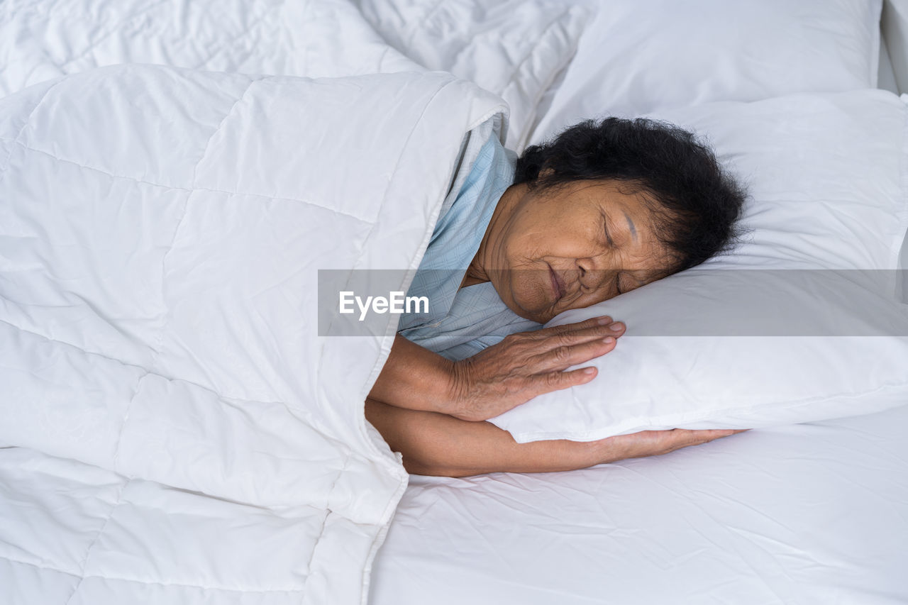 HIGH ANGLE VIEW OF BABY LYING ON BED