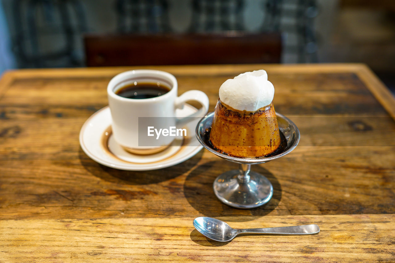 COFFEE CUP ON TABLE AGAINST WOODEN BACKGROUND