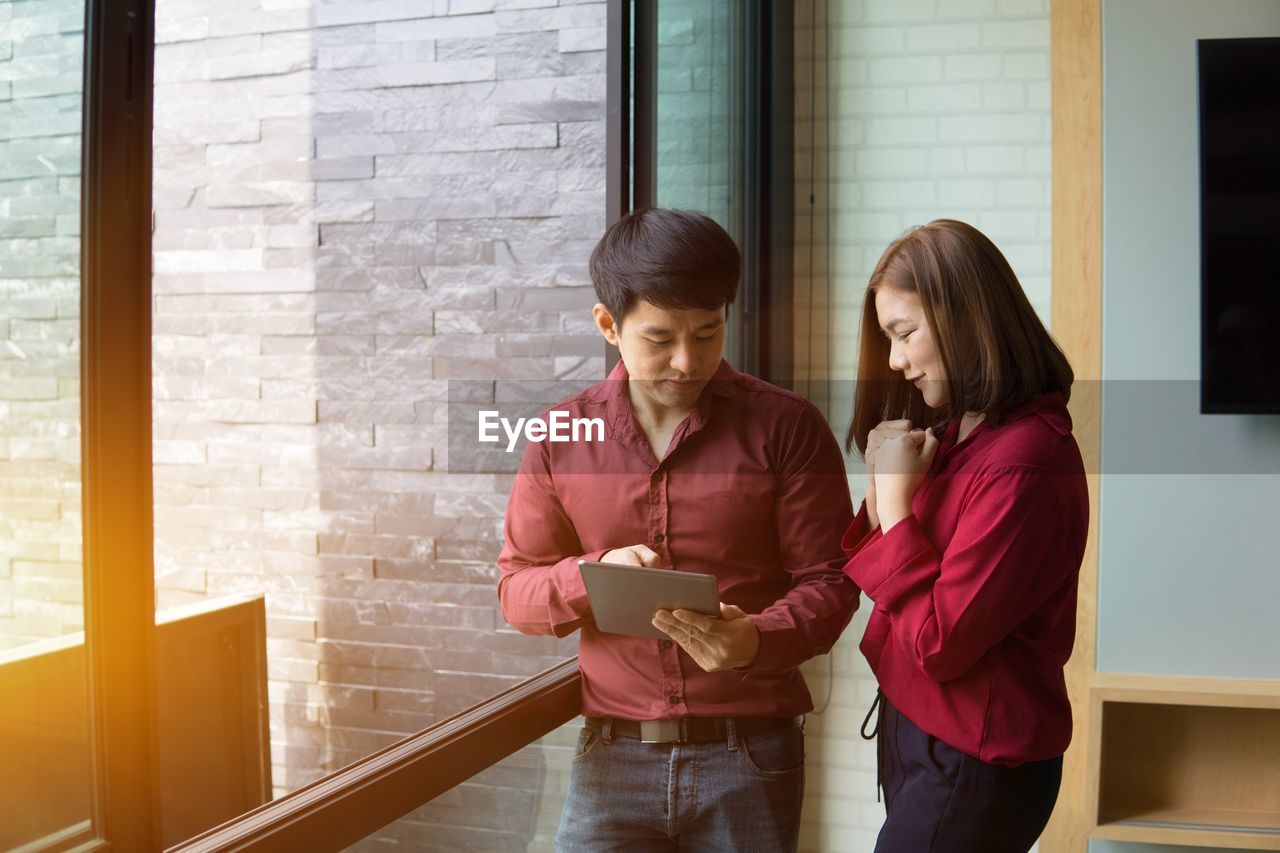 Business colleagues using digital tablet while standing in office