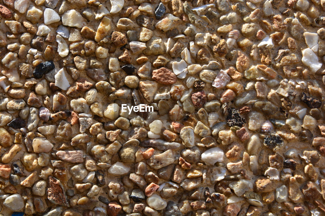 HIGH ANGLE VIEW OF PEBBLES ON WHITE SURFACE