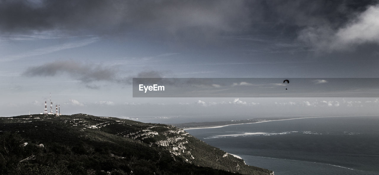 Scenic view of sea and mountain against cloudy sky