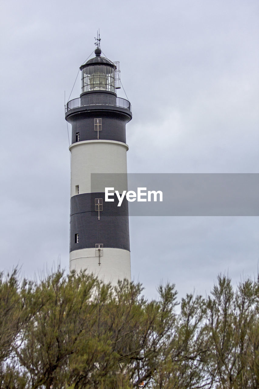 LOW ANGLE VIEW OF LIGHTHOUSE AMIDST TOWER AGAINST SKY