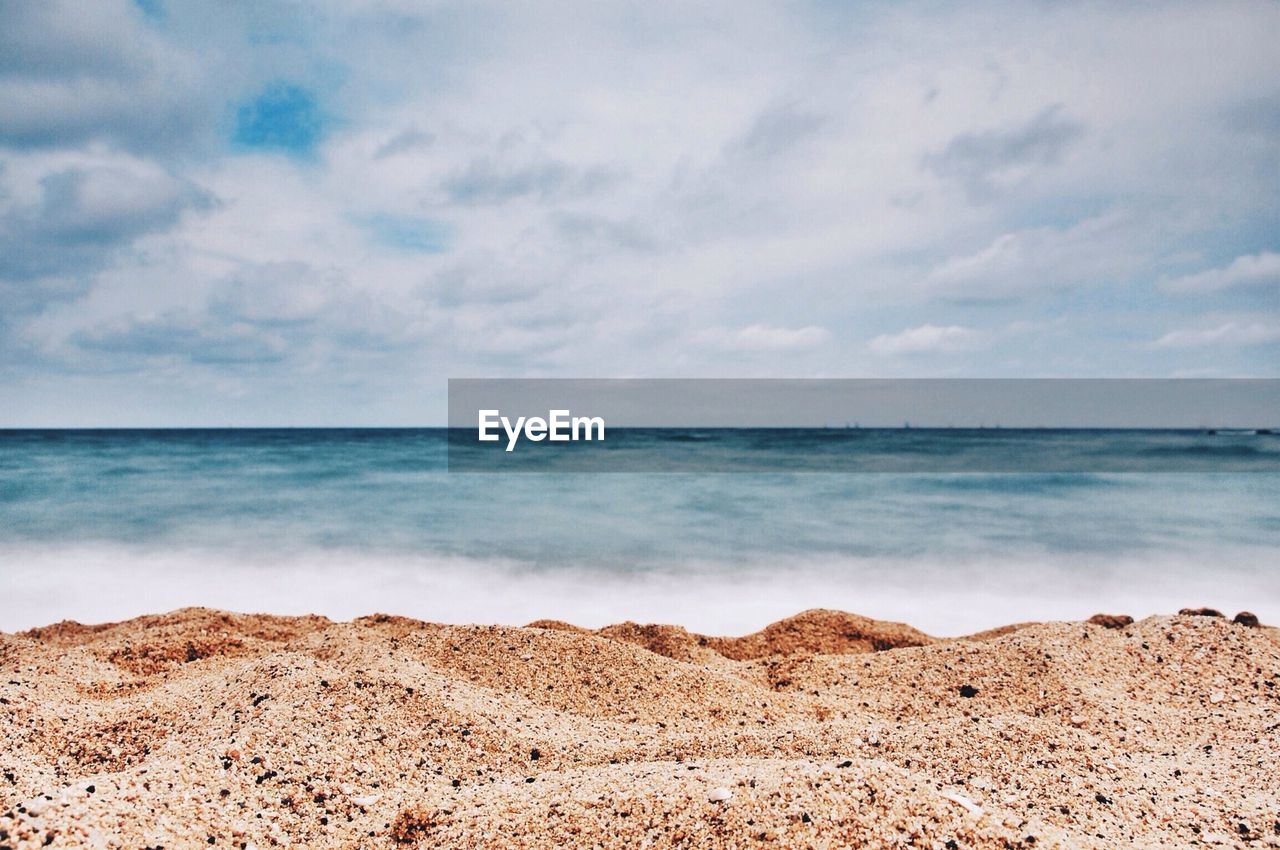 Scenic view of beach against cloudy sky