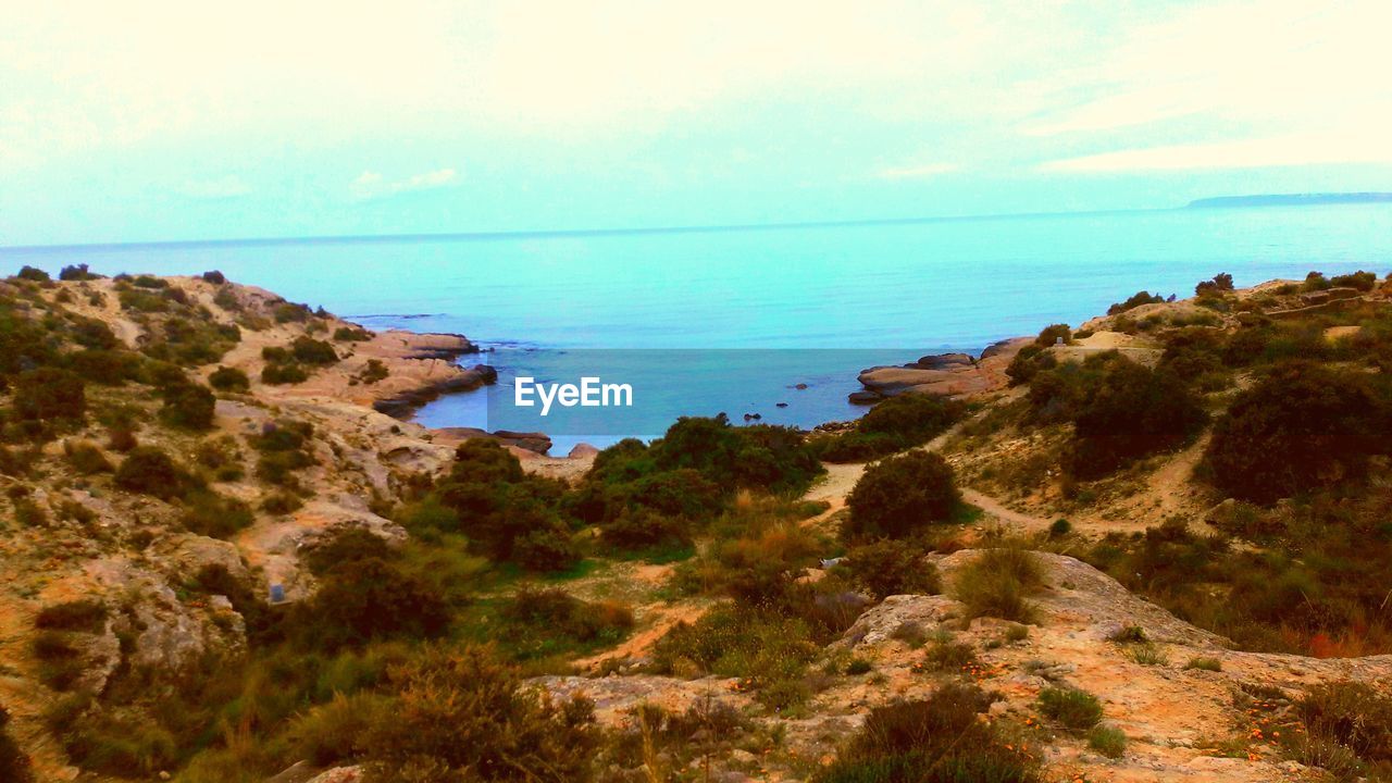 SCENIC VIEW OF SEA BY ROCKS AGAINST SKY