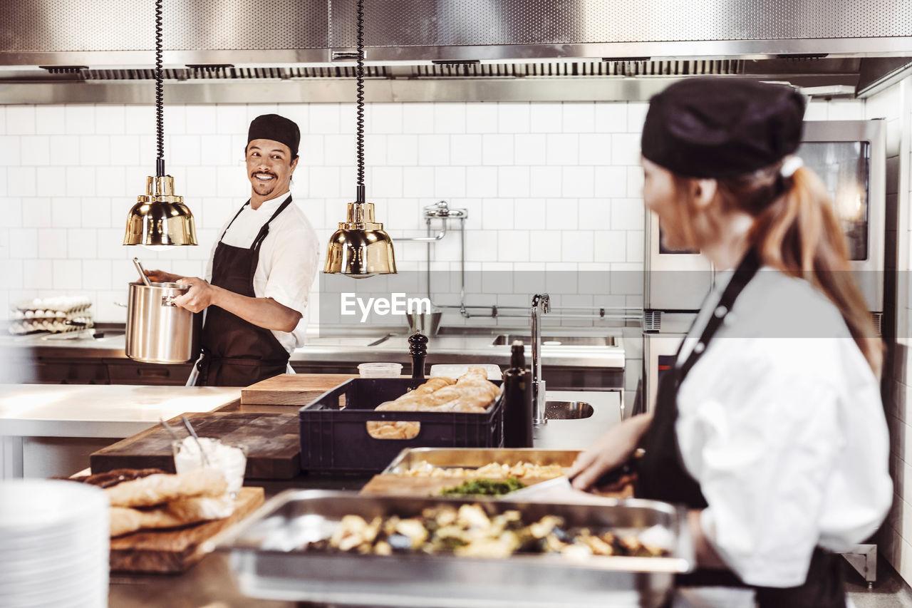 Smiling chefs looking at each other in commercial kitchen