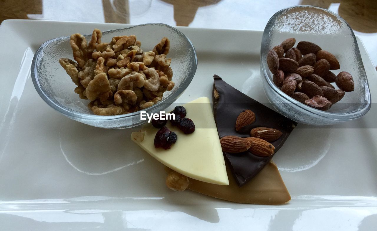 High angle view of walnuts and almonds with chocolates on serving tray
